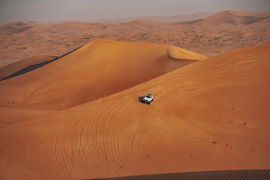 Off road safari vehicle driving across desert dunes